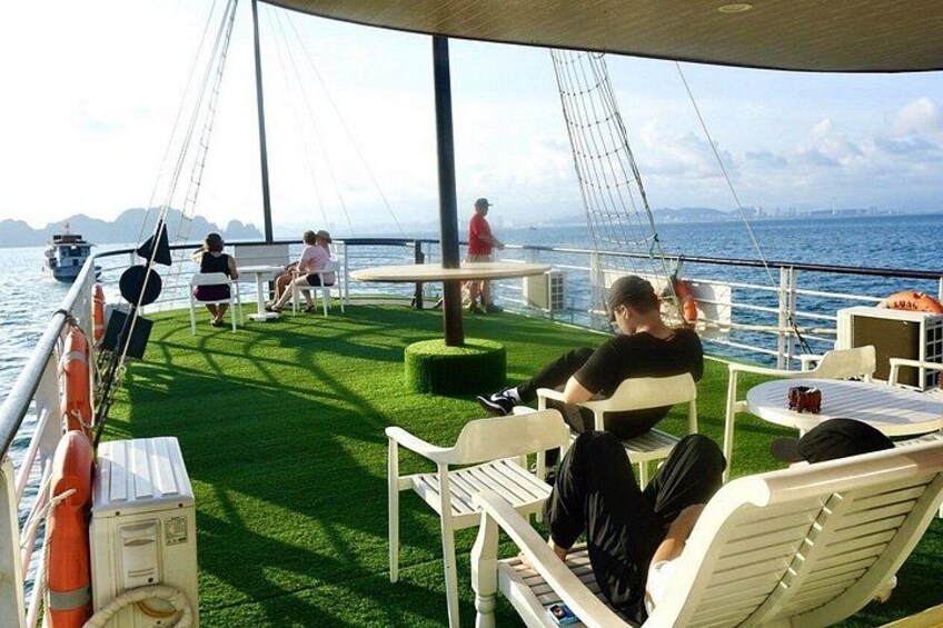A boat deck with artificial grass, white lounge chairs, and tables. 5