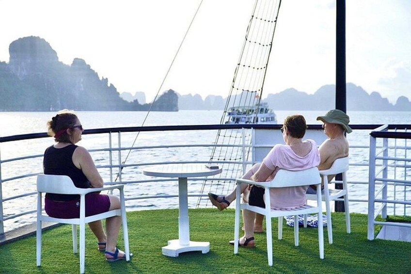 Three people sitting at a table on a boat with a view of a coastline. 2