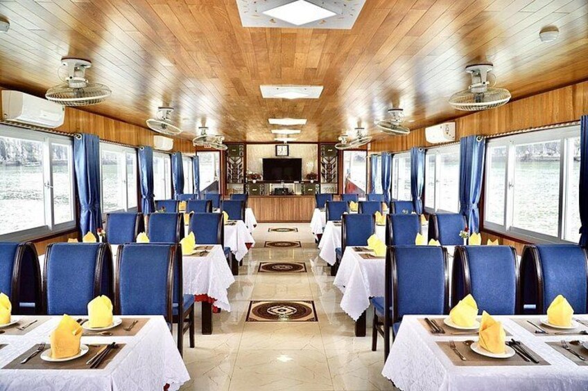 A restaurant with wooden walls and ceiling, blue chairs, white tablecloths, and yellow napkins. 4