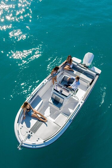 A small motorboat with three people on board, cruising on a turquoise sea. 3