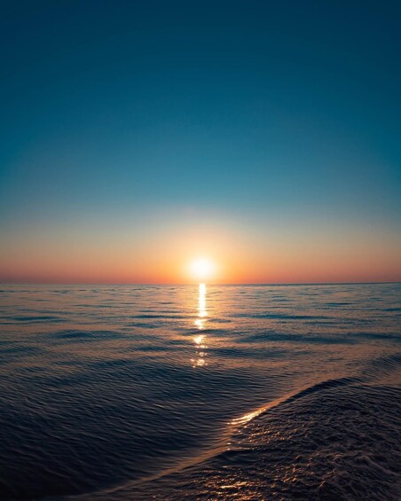 A sunset over a calm sea with gentle waves. 1