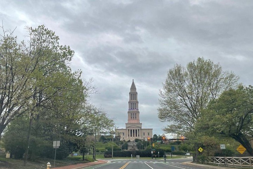 A tower with a clock, surrounded by trees and a road. 2