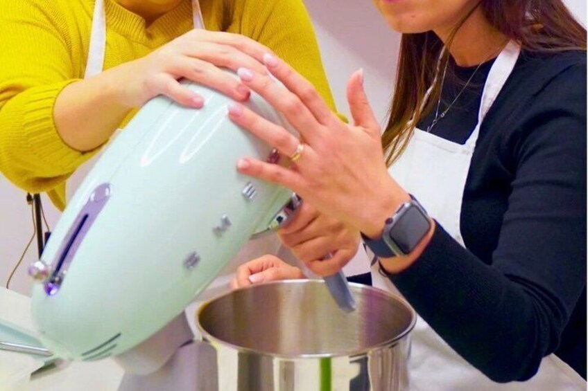 Two people preparing food, one using a light blue kitchen appliance and the other stirring a pot. 5