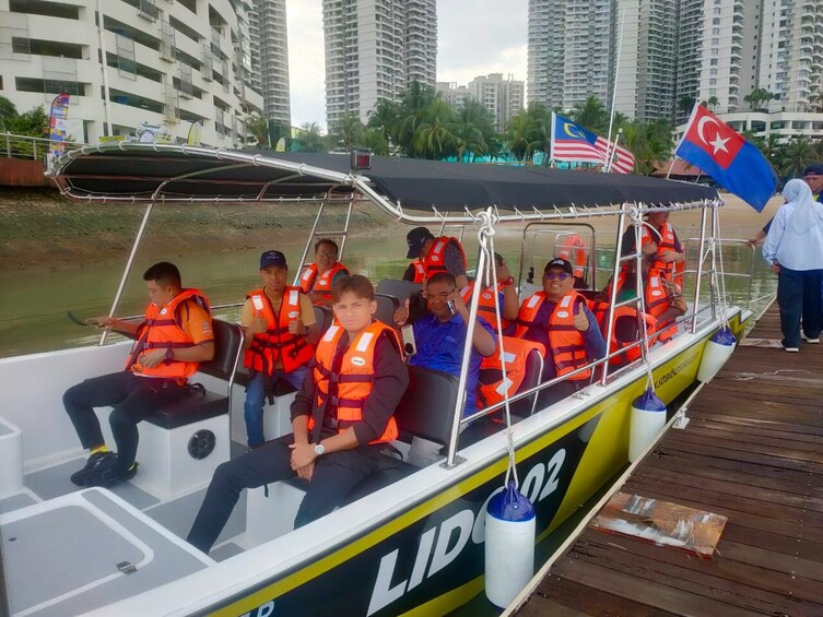 A boat with passengers wearing life jackets, docked at a pier with city buildings in the background. 2