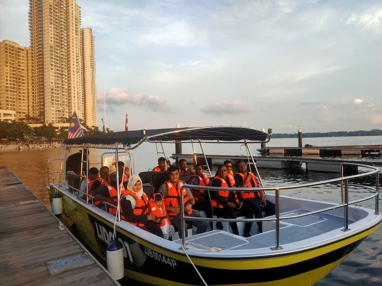 A boat with passengers wearing life jackets docked at a pier with a city skyline in the background. 1