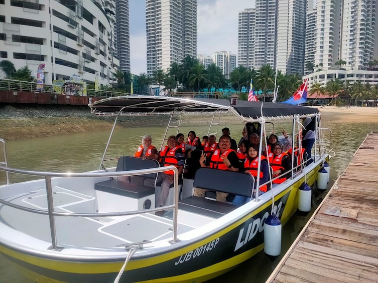 A boat with passengers wearing life jackets docked at a pier with high-rise buildings in the background. 3