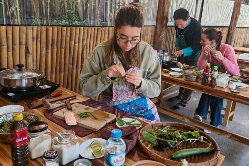 A person preparing food at a wooden table with various ingredients and utensils. 4