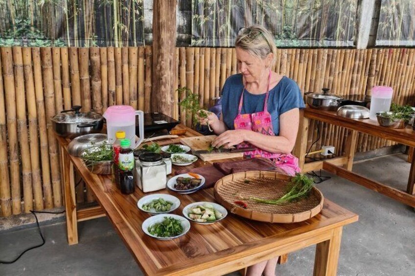 A person preparing food at a wooden table with various ingredients and cooking utensils. 1