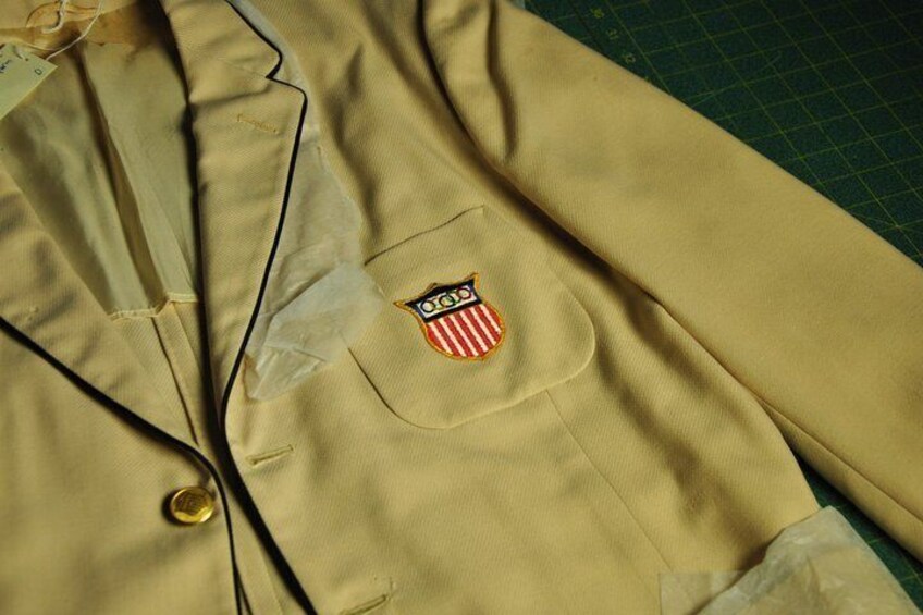 A beige jacket with a patch on the left chest and a button. 4