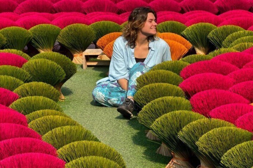 A person sitting amidst rows of colorful artificial flowers. 3