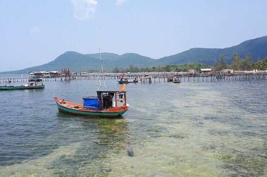 A small boat in a calm body of water with clear visibility to the shore. 4