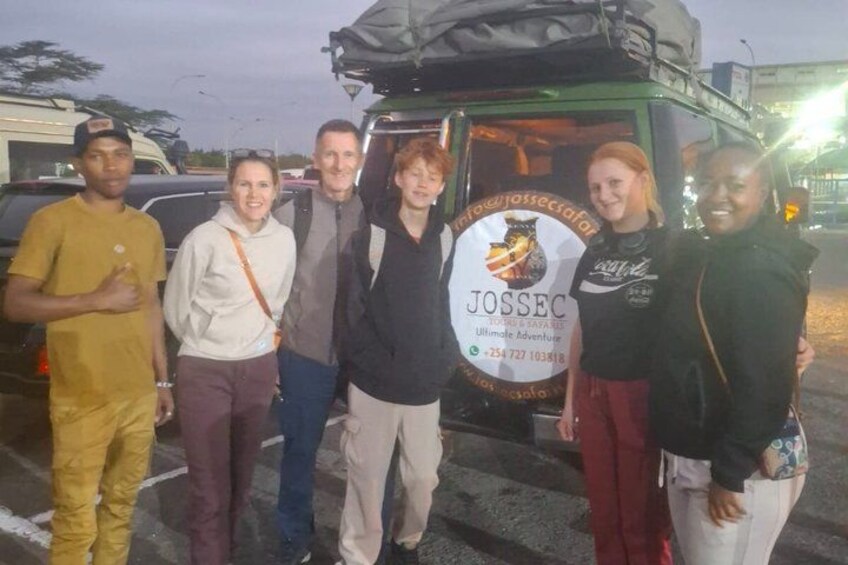 A group of people standing in front of a vehicle with a logo and contact information. 1