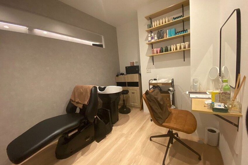 A modern salon interior with a massage table, a massage chair, shelves with beauty products, and a mirror. 3