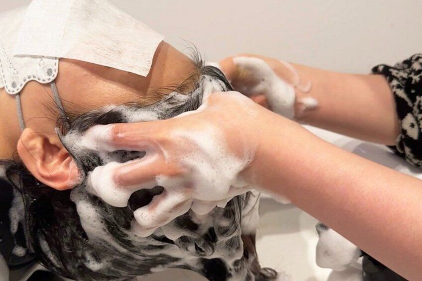 A person receiving a hair treatment with a foamy substance. 5
