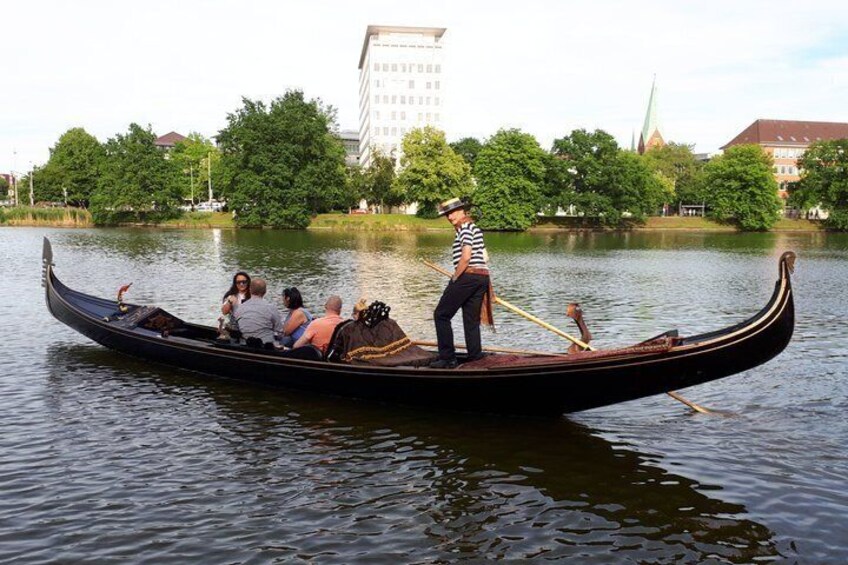 A gondola with passengers and a gondolier on a calm river. 4