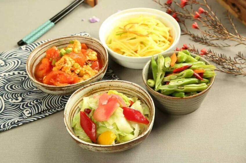 Three bowls of food with chopsticks and a patterned mat. 5