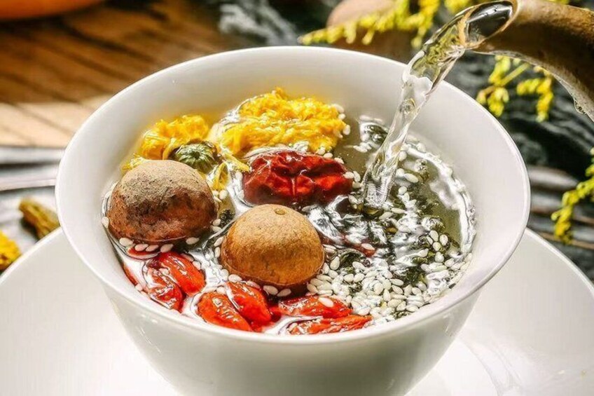 A bowl with various ingredients being added to a liquid, possibly a soup or stew. 4
