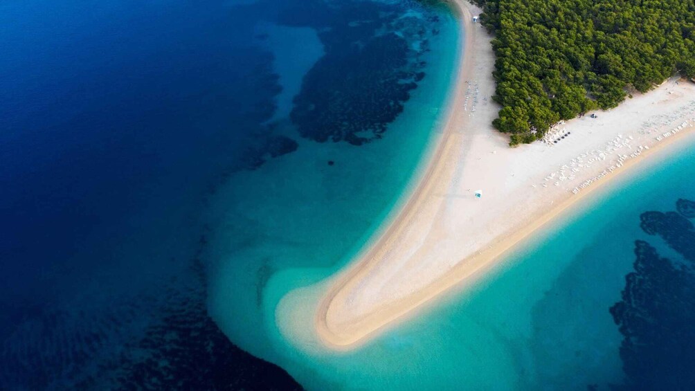 A turquoise coastline with a sandy beach and dense forest. 1