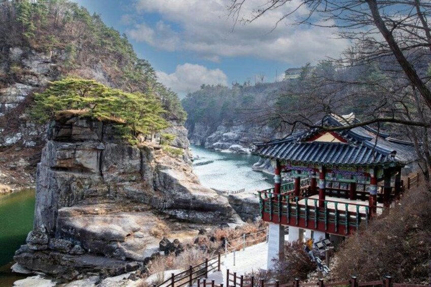 A traditional Korean pavilion overlooking a river, with rocky cliffs and a mountainous landscape. 2