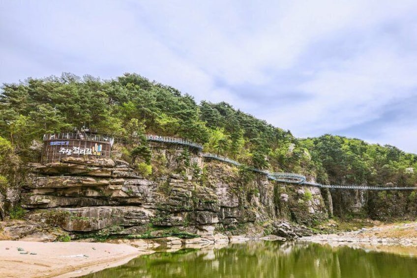 A suspension bridge over a river, surrounded by rocky cliffs and dense forest. 1