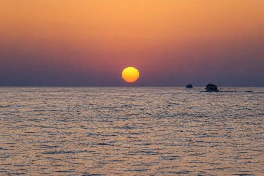 A sunset over the ocean with two boats. 4
