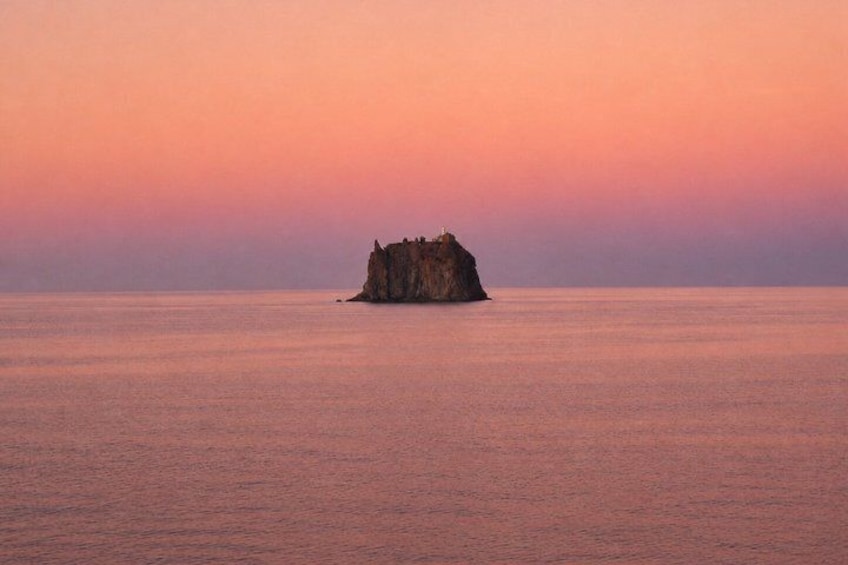 A solitary rock formation in the sea during sunset. 3