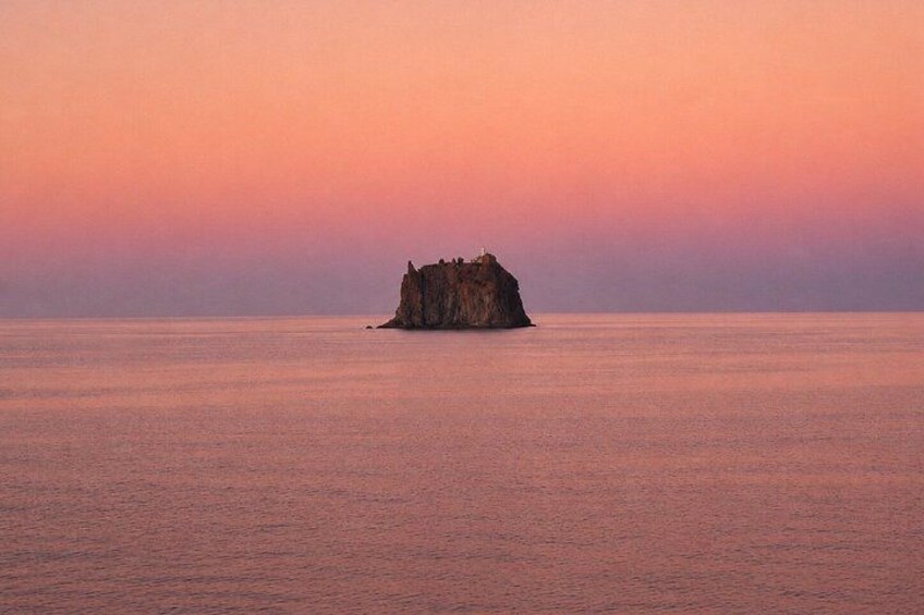 A rocky island with a clear sky at sunset. 5