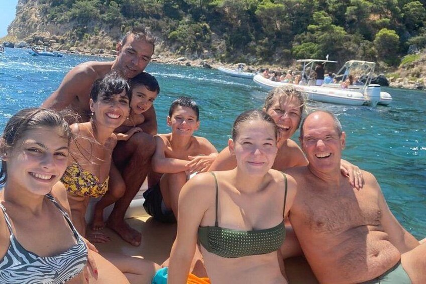 A group of people on a boat in a body of water with a rocky coastline in the background. 1