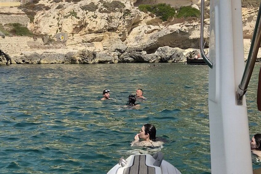 People swimming in a body of water with rocky cliffs in the background. 4