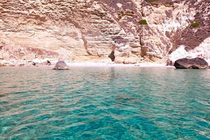 A clear turquoise sea with rocky cliffs and a few scattered rocks. 4