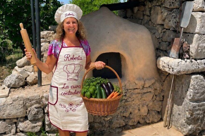 A person with a chef's hat and apron standing in front of a stone oven, holding a rolling pin and a basket of vegetables. 2
