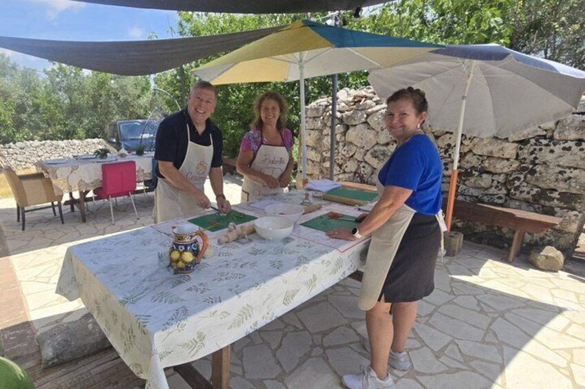 Two people at an outdoor table with a tablecloth, a cutting board, and a bowl. 4