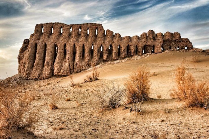A desert landscape with a large rock formation featuring multiple holes. 1