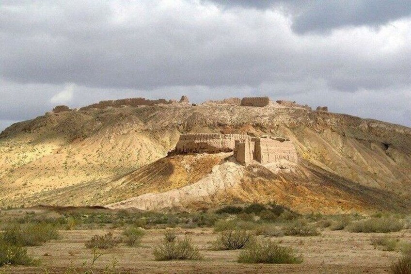 A desert landscape with a large hill and a small building on top. 4