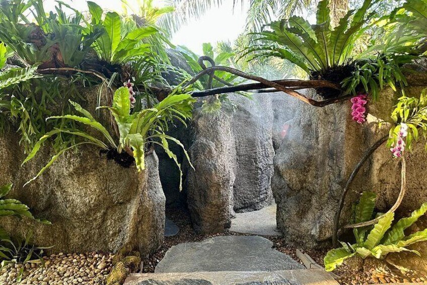 A rock archway with lush greenery and flowering plants. 3