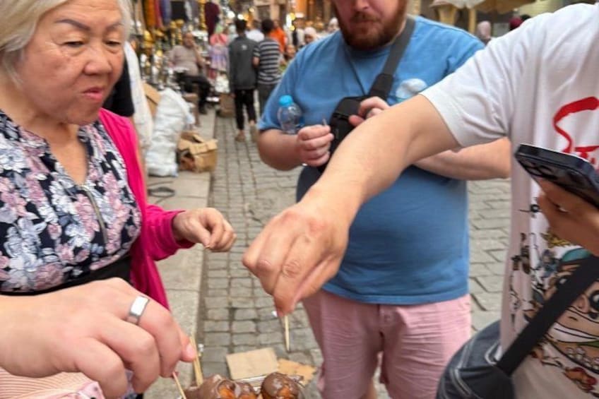 A street market with people shopping and a vendor serving food. 4