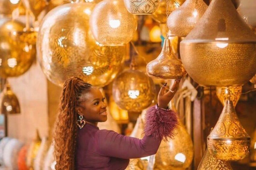 A person examining ornate, golden-colored lamps. 5