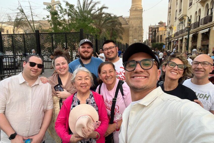 A group of people posing for a photo in an urban setting with historical architecture. 2