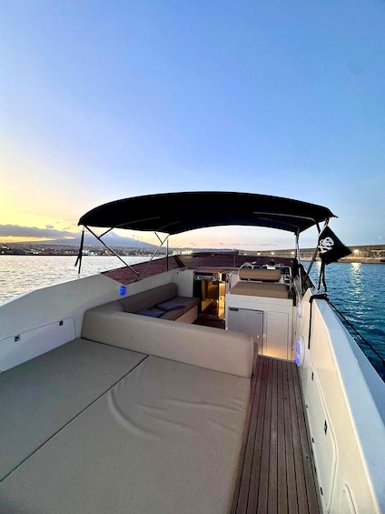 A boat deck with seating and a canopy, water in the background, and a clear sky. 2