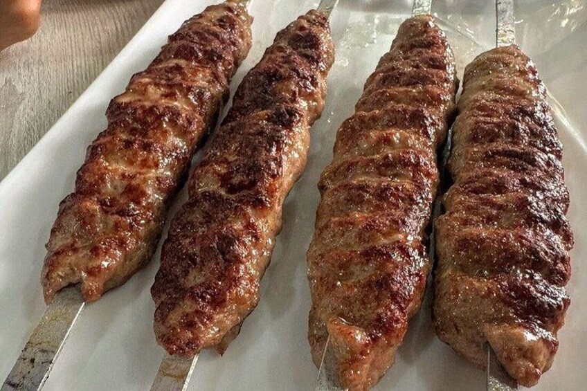 Four grilled kebabs on a white plate. 3
