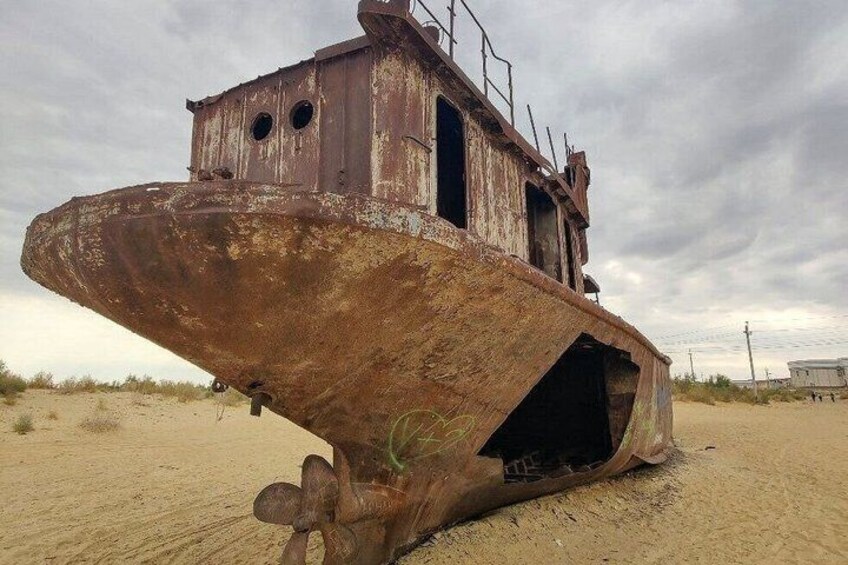 A rusted, abandoned shipwreck on a sandy beach with overcast skies. 5