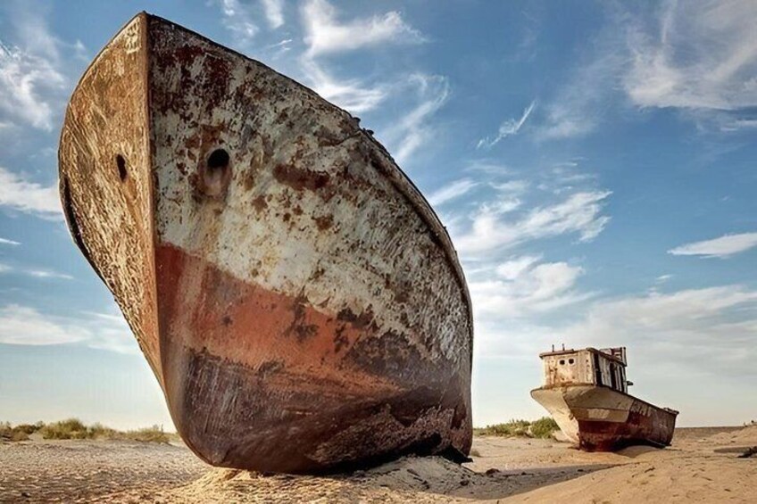 A rusted boat on a sandy beach with a clear sky. 1
