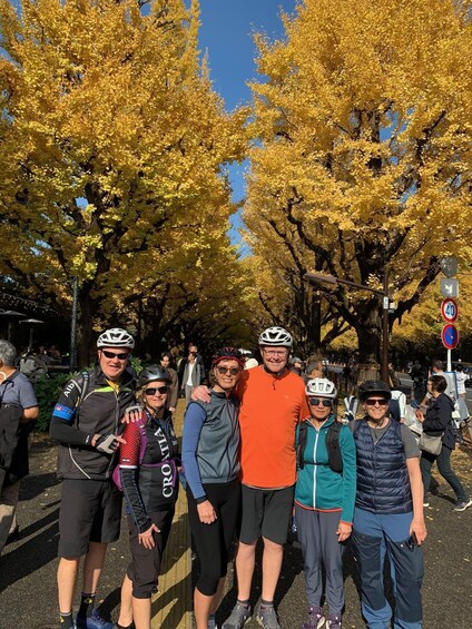 A group of cyclists in a park with yellow trees. 5