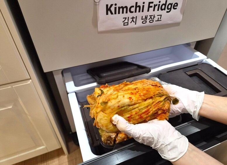 A person holding a kimchi fridge with a sign in Korean. 3