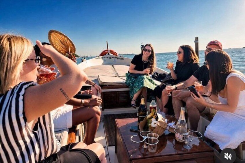 A group of people on a boat with drinks and a bottle of champagne. 5