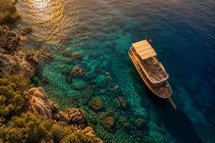 A boat anchored near a rocky coastline with clear turquoise waters. 4