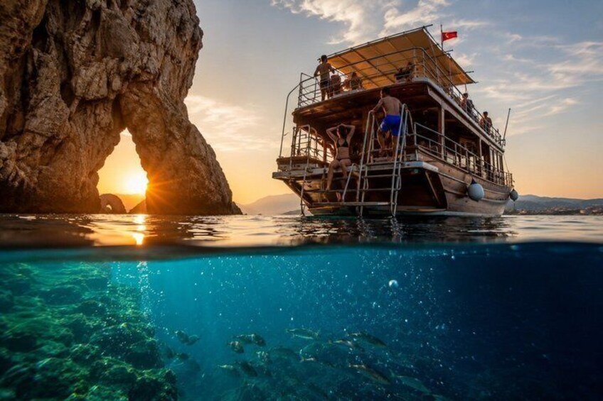 A boat anchored near a rock formation with a clear blue sea. 4