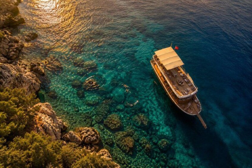 A boat anchored near a rocky coastline with clear blue water. 3