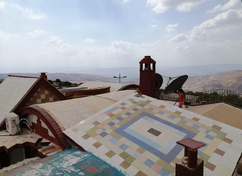 A rooftop with a checkered pattern, a satellite dish, and a bell tower. 1