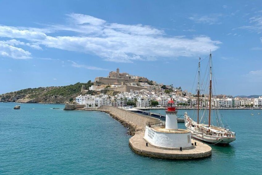 A coastal town with a lighthouse, boats, and a historic building on a hill. 5